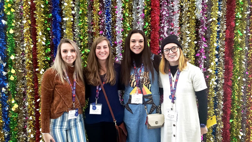 standing in front of colorful handing tinsel decoration backdrop