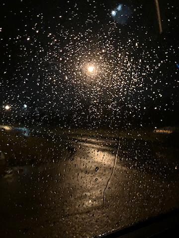 Photograph of rain on a glass window at night.