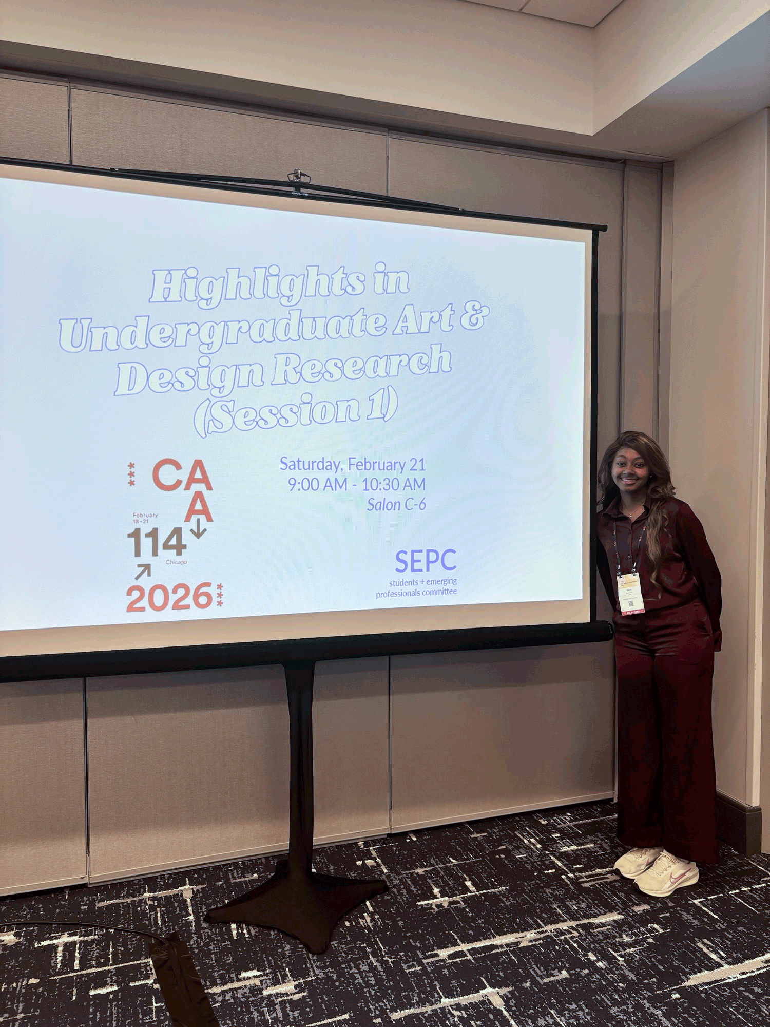 Rayne Lewis posing next to the 114th CAA Conference presentation board.