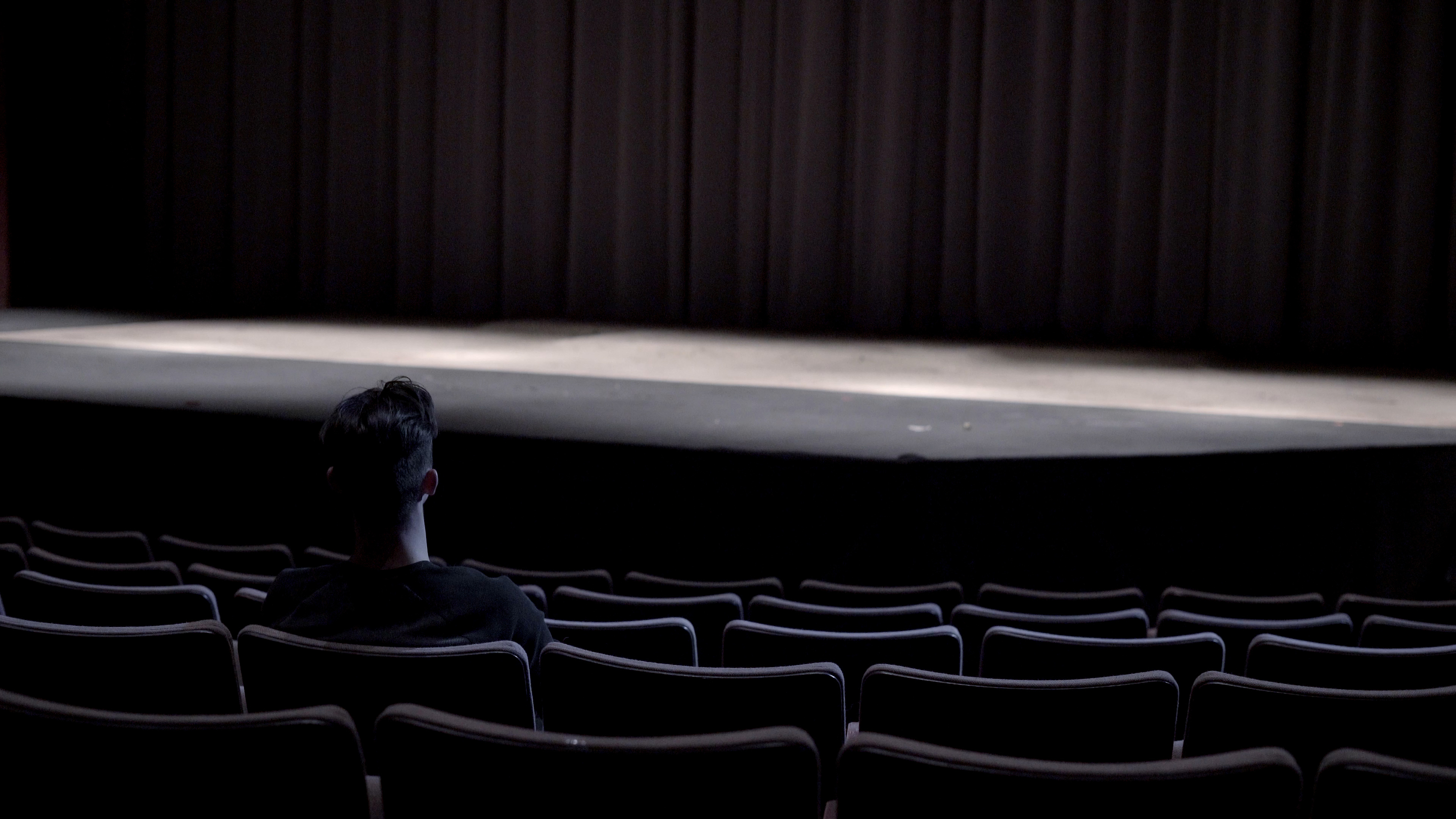 Photograph of a person sitting in a movie theatre.