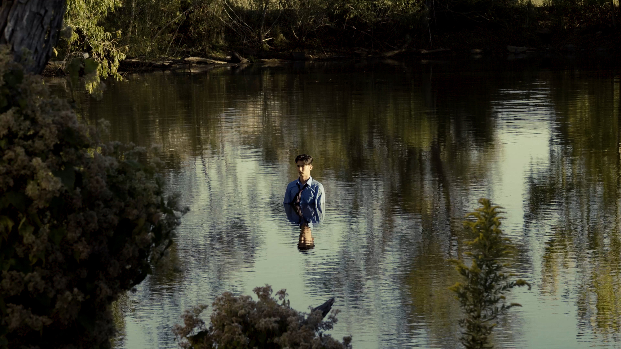 Photograph of a person standing chest deep in a body of water.