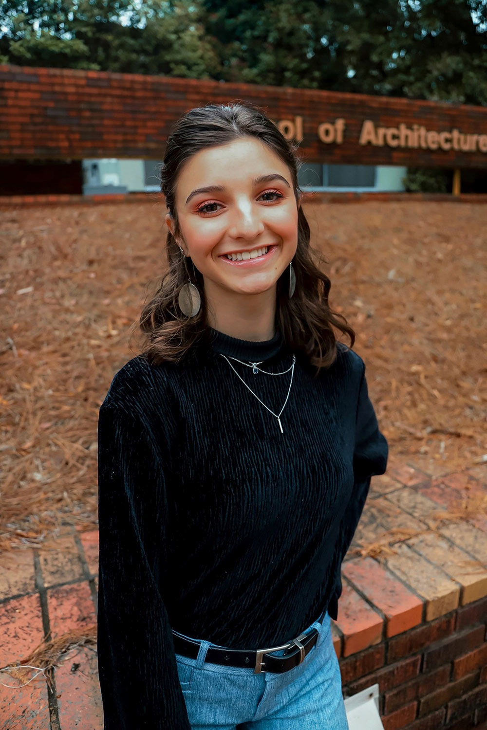 Annelise Sernich poses in front of the "Architecture" sign outside of Giles Hall at Mississippi State University