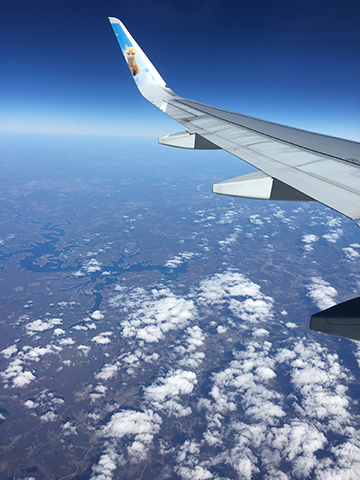 Photograph of the wing of an airplane over clouds.