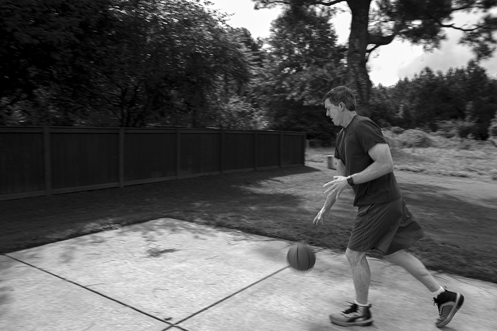 A black and white photographed image of a man dribbling a basketball.