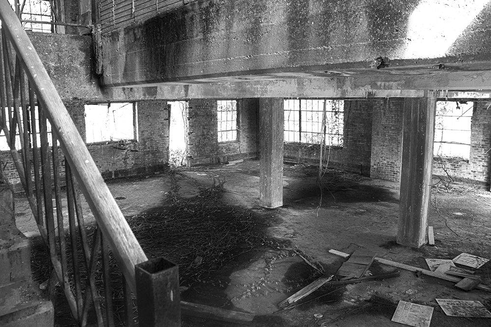 A black and white photographed image of the inside of an abandoned building 