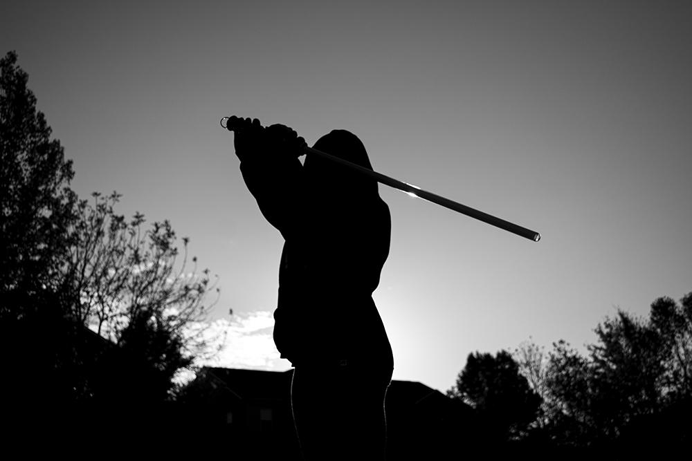 A black and white photographed image of a person holding a baseball bat. 