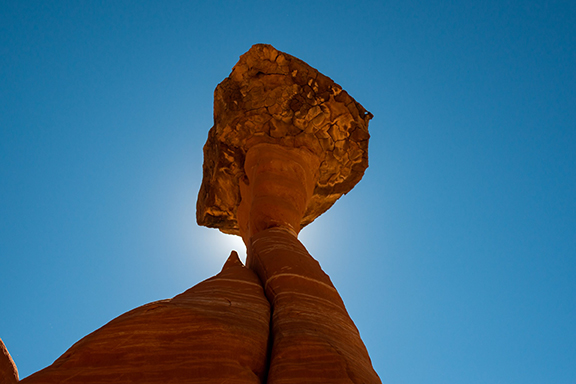 Photograph of an orange rock formation against the blue sky.