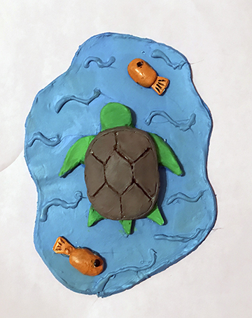 Clay sculpture of a turtle in a pool of water.