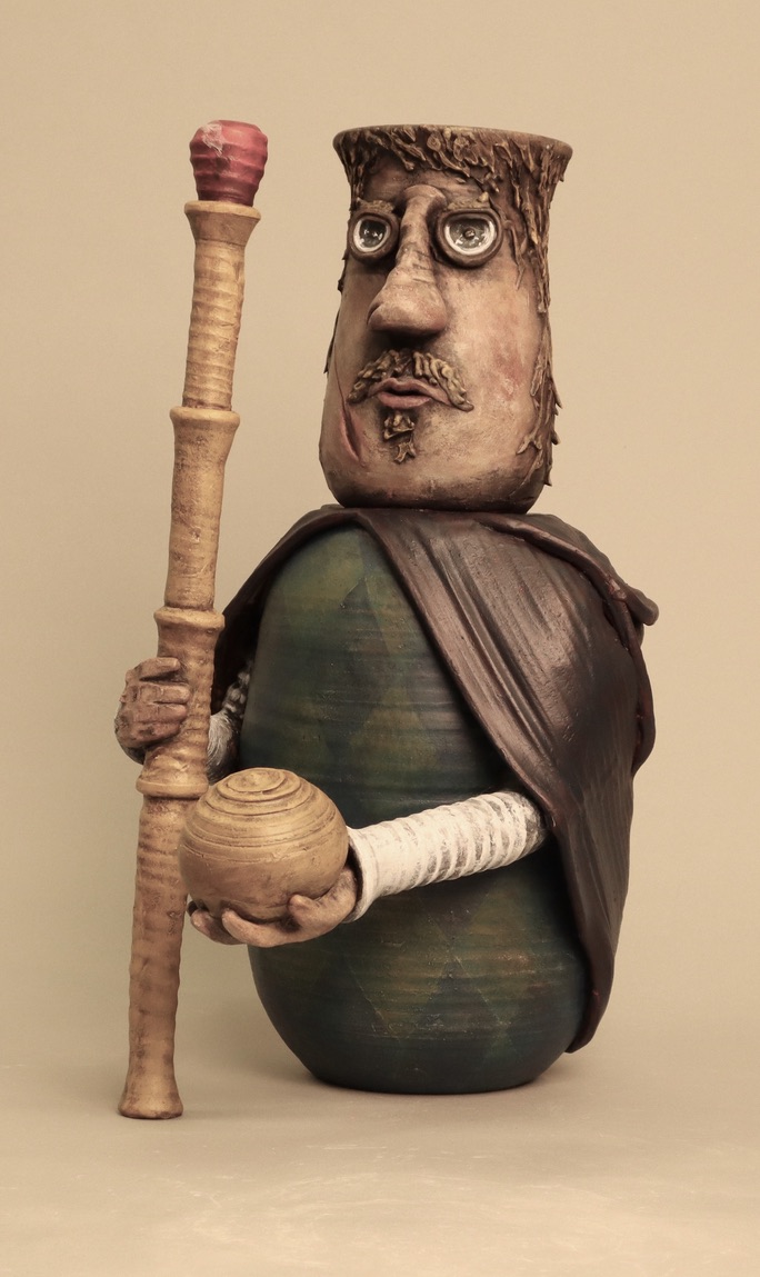 Ceramic bust of a king holding a yellow scepter and globe while wearing green harlequins and a burgundy cloak.