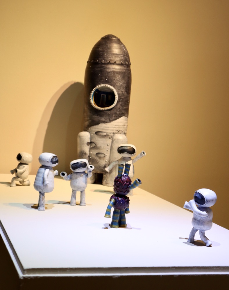 Ceramic rocketship with 5 white astronauts and a red, green, and blue alien