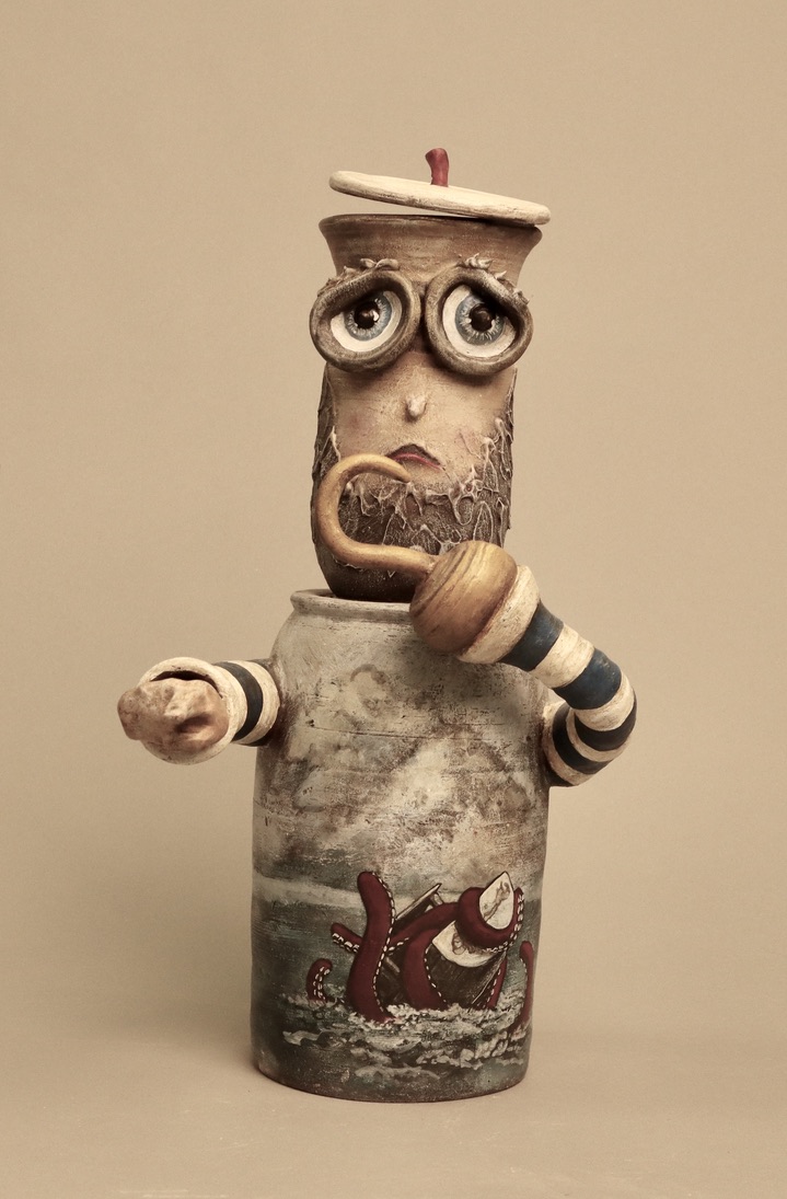 Ceramic french sailor reveals a hook for a hand while the other hand points to the distance