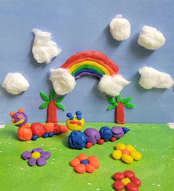 Clay collage of a caterpillar and rainbow.