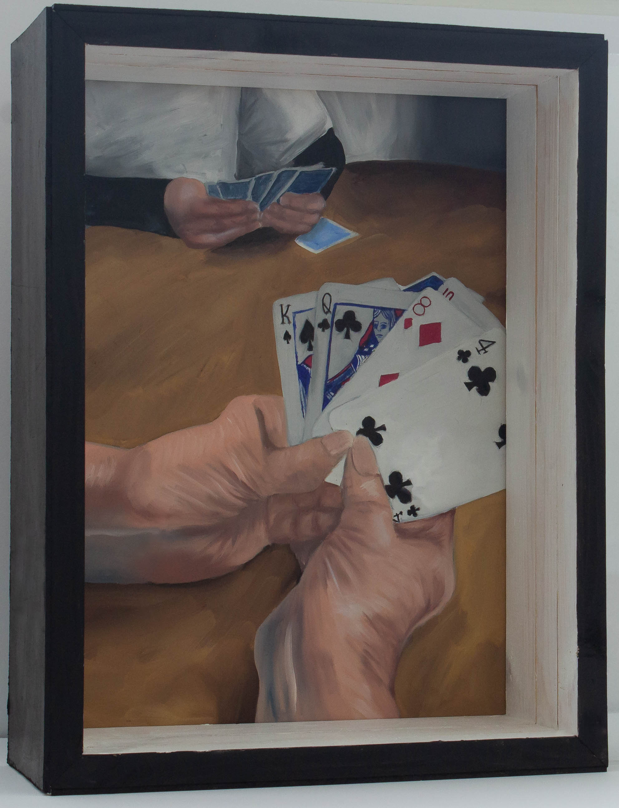 A box with a painting in the back and treated plexiglass panels interfering with the view of the painting. The painting shows an older person’s hands holding playing cards, they are a king, a queen, an eight, a four, and a ten. There is another person sat across from the hands playing the game as well. Both panels are slid out of the box. The painting is no longer obstructed by the plexiglass. The frontmost hands are wrinkly and veins are visible. They are both playing on a wooden table. The person in the back is wearing a white t-shirt and the back of their cards are blue. 