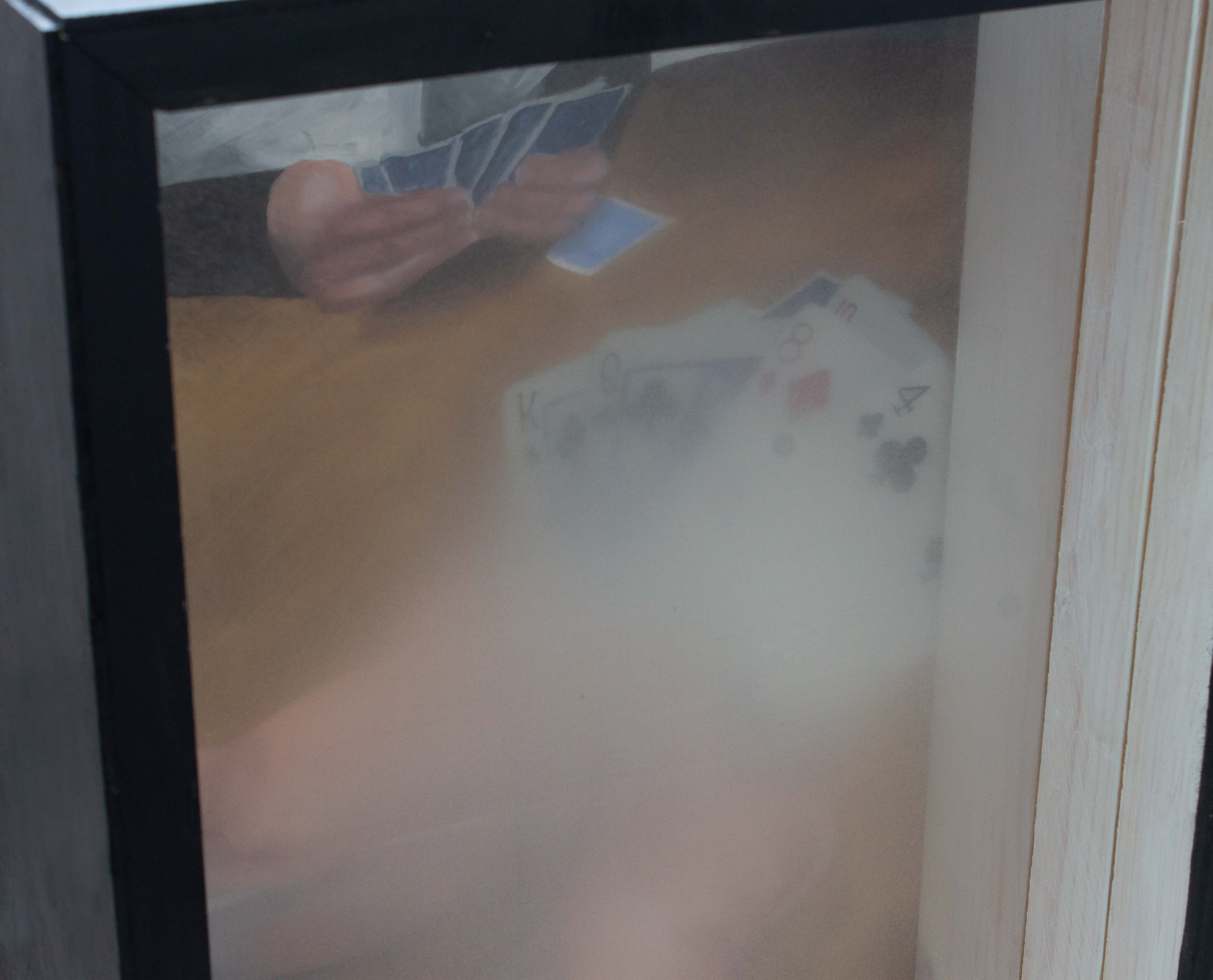 A detail image of the top left corner of the piece. A box with a painting in the back and treated plexiglass panels interfering with the view of the painting. The painting shows an older person’s hands holding playing cards. There is another person sat across from the hands playing the game as well. Both panels are in front of the painting. Up close the treatment of the plexiglass can be seen more, it is very smooth, fuzzy, and opaque.