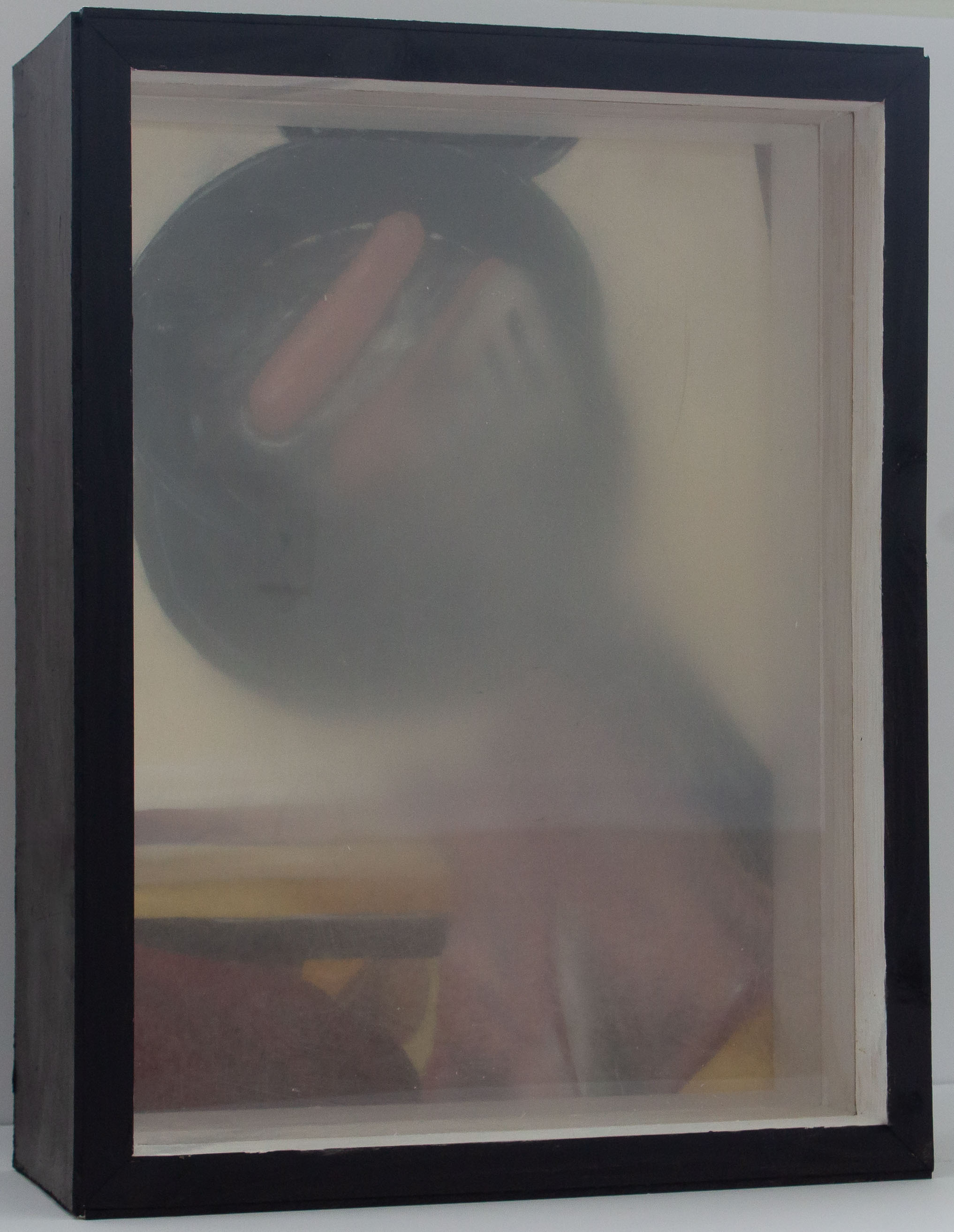 A box with a painting in the back and treated plexiglass panels interfering with the view of the painting. The painting shows an older person’s hand as they cook two hotdogs on a skillet. The person is holding a spatula. They are wearing a red shirt. The stove top surrounding the eye being used is visible. Both panels are in front of the painting. The front most panel of plexiglass is fuzzy and smooth. The back panel of plexiglass is rough, scratched, and blurry. Both panels are blurry more in the center and fade out.