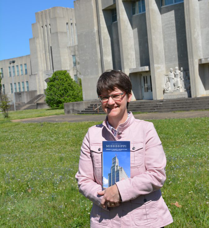 Jennifer Baughn holds "Buildings of Mississippi" and poses for a photo in front of historic building