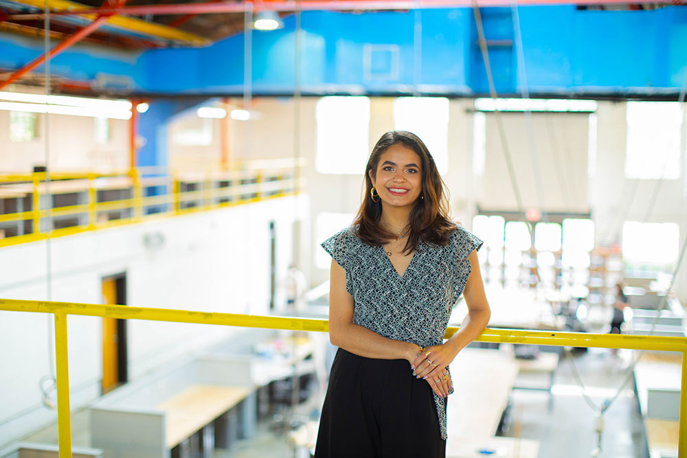 Elisa Castaneda poses by railing upstairs in Giles Hall (overlooking Barn)