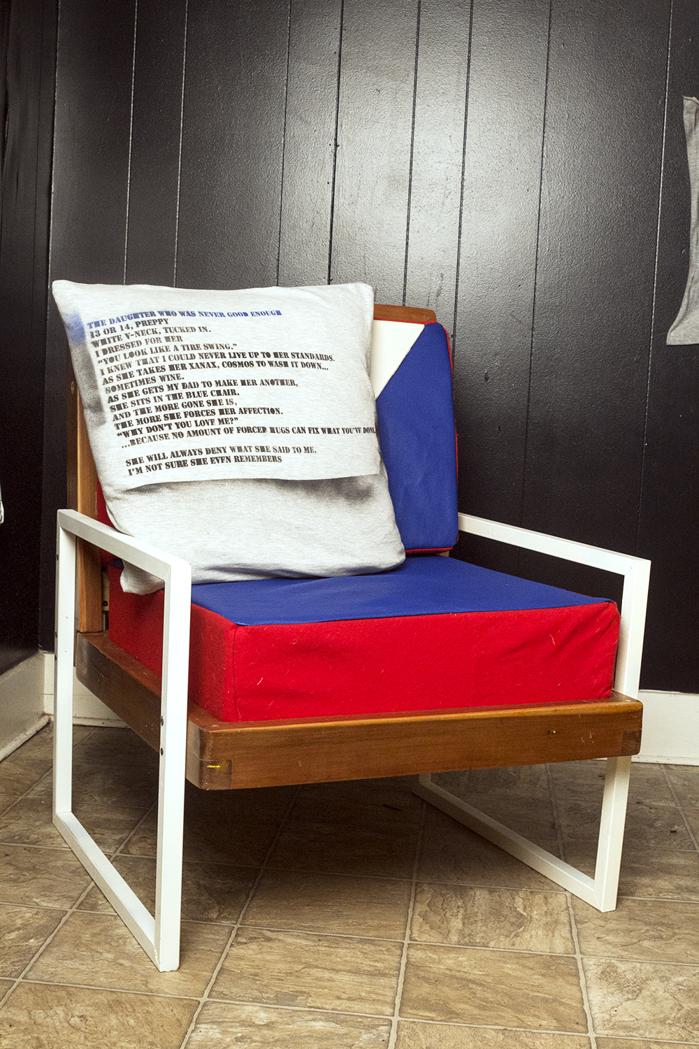 chair with steel legs that are also arm rests, cushions are leather with felt sides, framing is wood. pillow on chair has stenciled poem on it. 