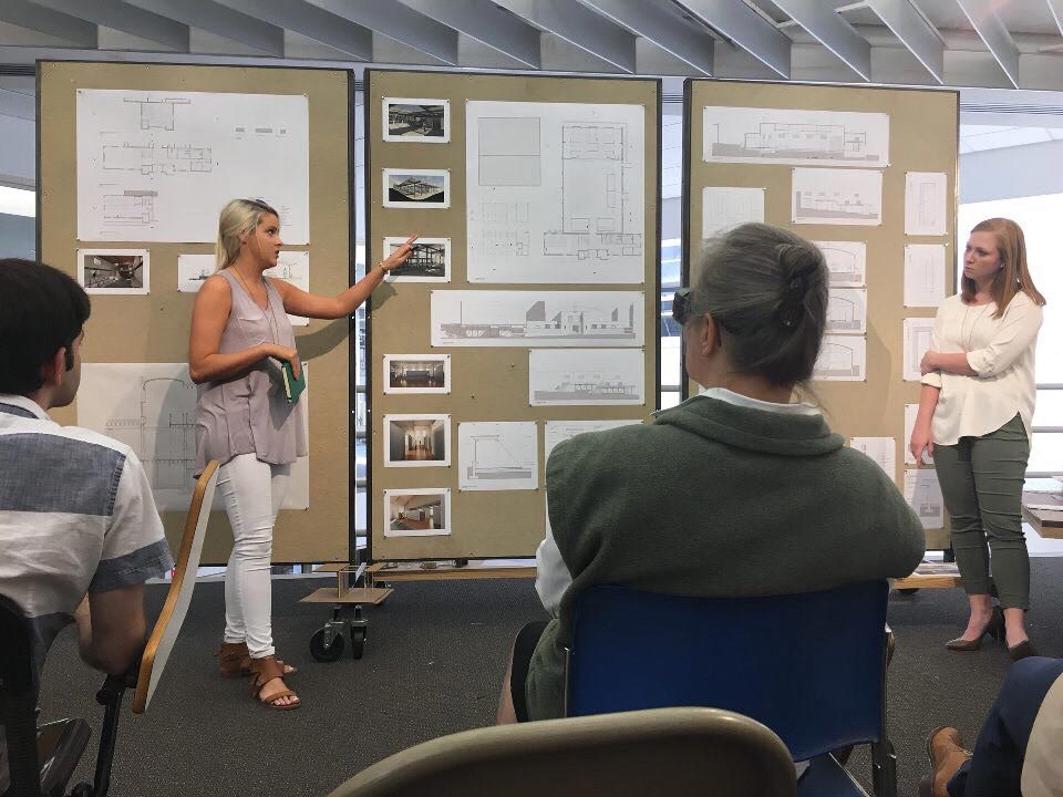 Students talking about their work to a crowd of people