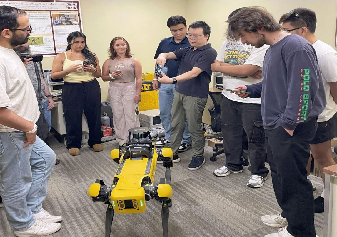 Hands on Robotics session with Boston Dynamics' Spot Robodog. Image shows group gathered around looking at yellow robot dog