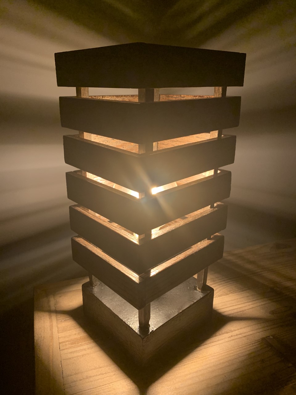 A bulb covered with wooden slats that allow light to shine through.