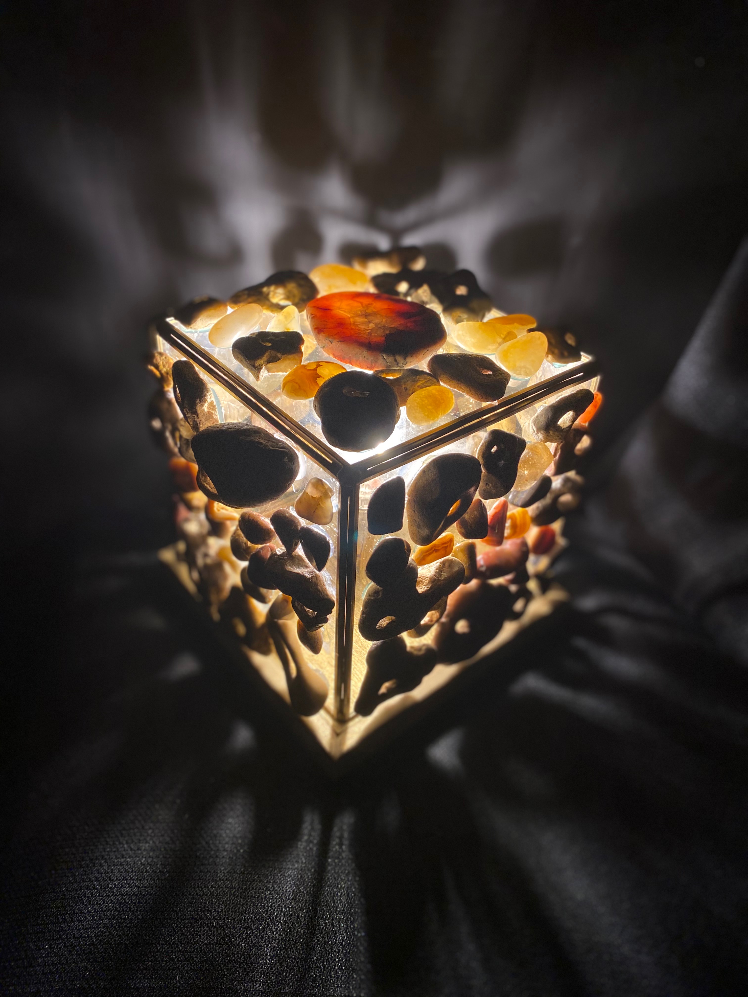 Image of a lamp created by covering a box with different colored stones that light shines through.
