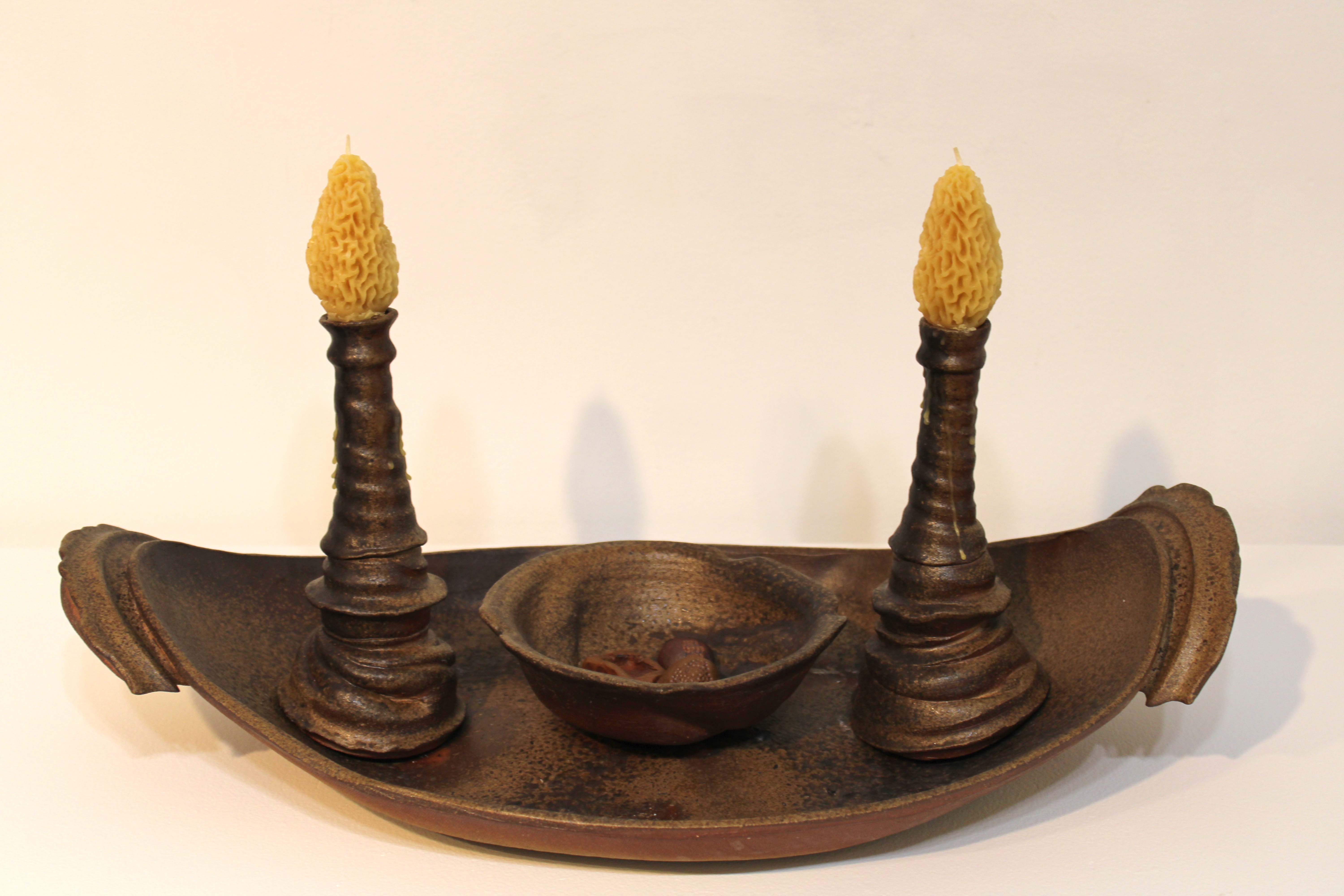 Curved platter with candlestick holders and bowl. Bowl contains small trinkets. Candlestick holders contain beeswax candles.