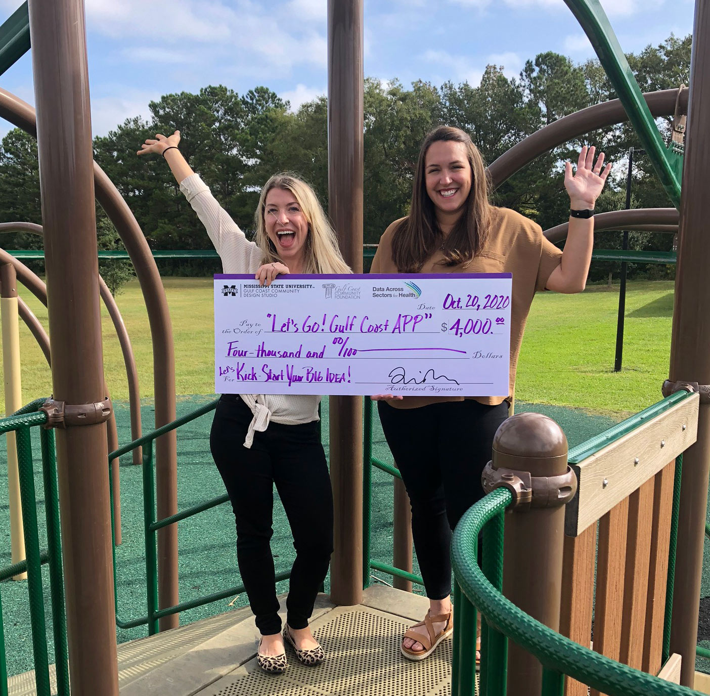 Cathryn Wineski and Kelsey Keel with Let’s Go! Gulf Coast hold giant check