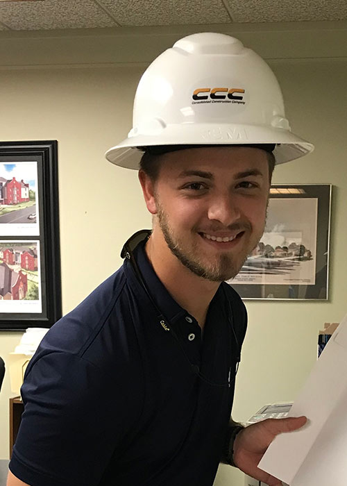 Garrett Jones sits at desk wearing hard hat
