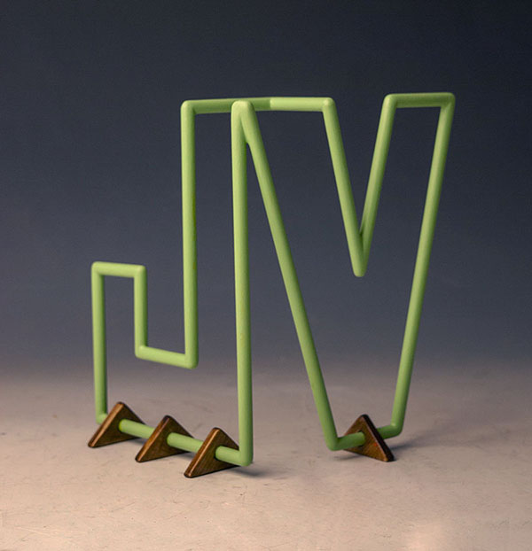 Sculpture of the letters "JV" made from wooden dowels painted green.
