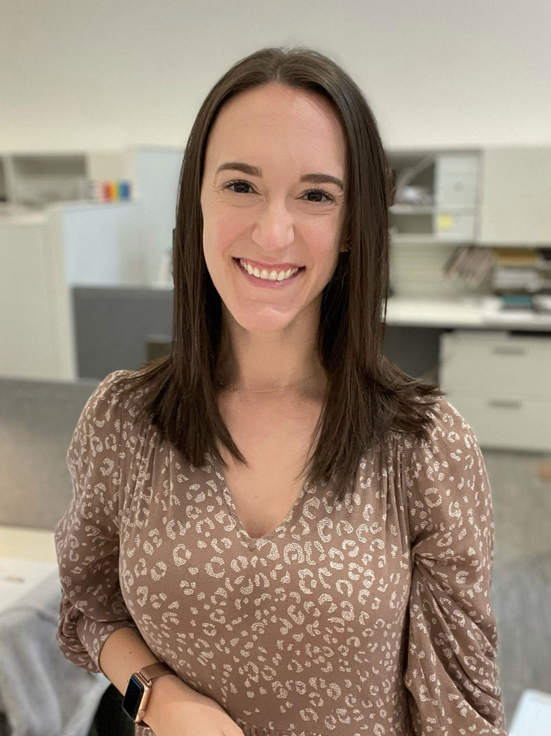 Kate Berryman smiling, wearing a tan and white-animal print shirt.