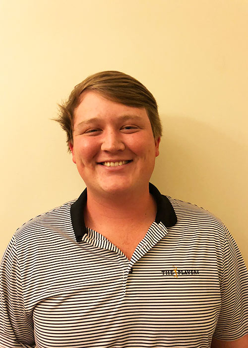 Kyle Murphy poses in front of light wall wearing small-striped collared shirt