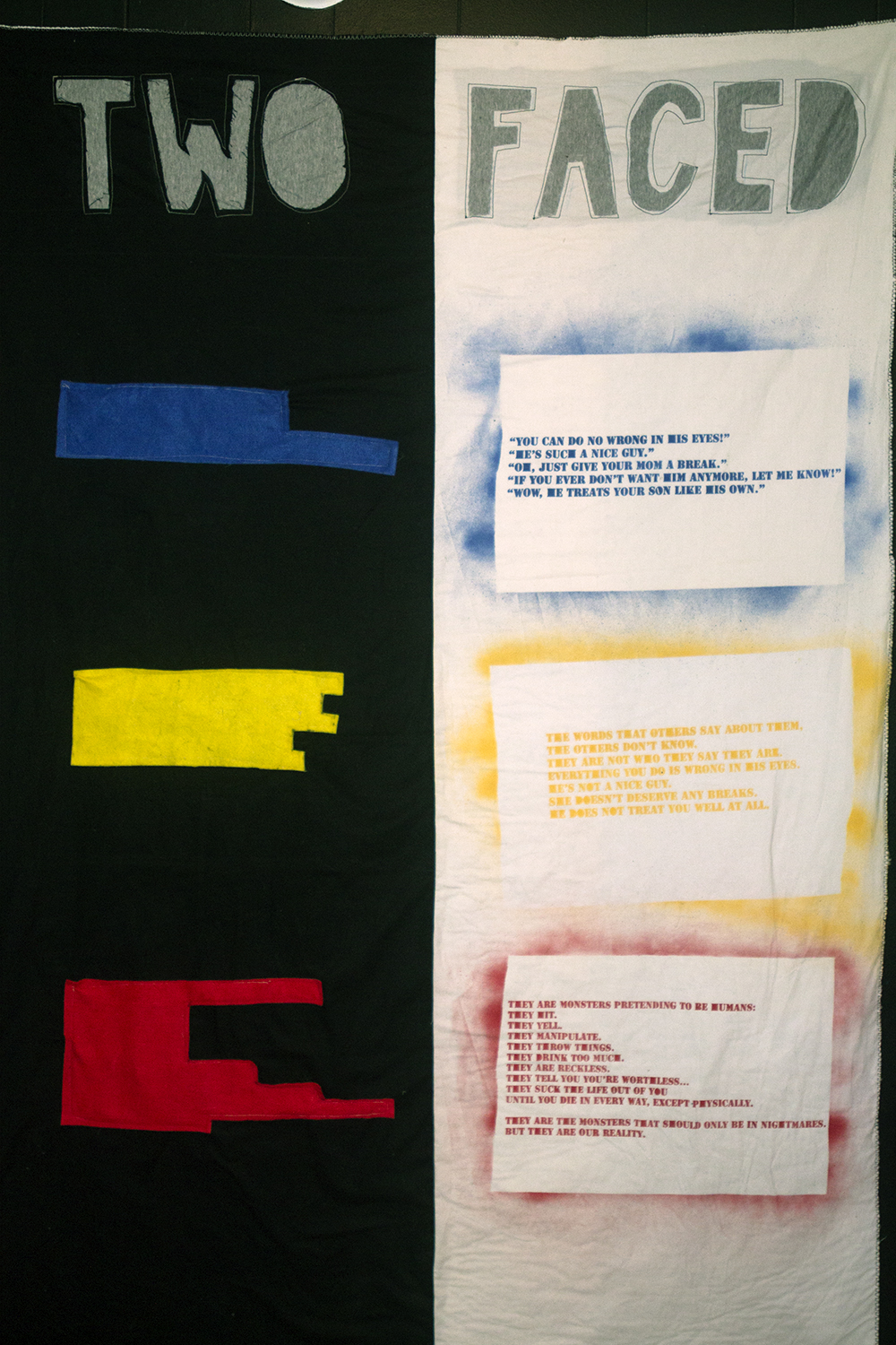 quilt divided in half, one side with stenciled on poem and the other with shapes that resemble the shape of the poem with no words. at the top it says two faced.