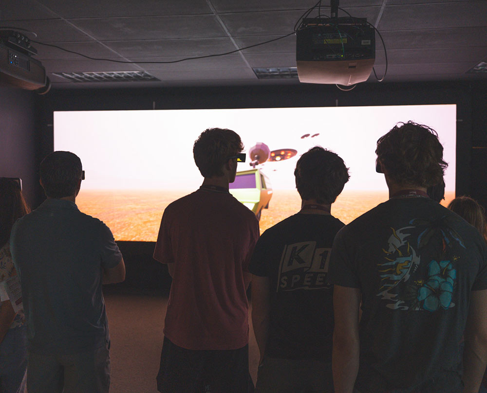 A group looks at a screen in a VR lab wearing VR headsets