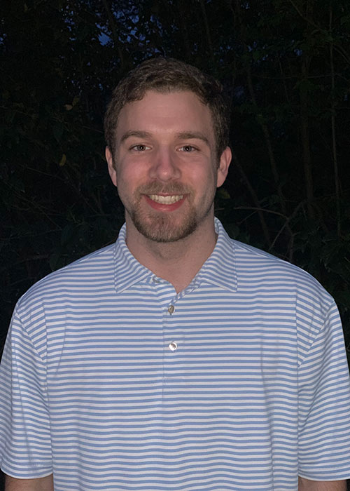 Jacob Stovall headshot - wearing blue striped collard shirt outside at night