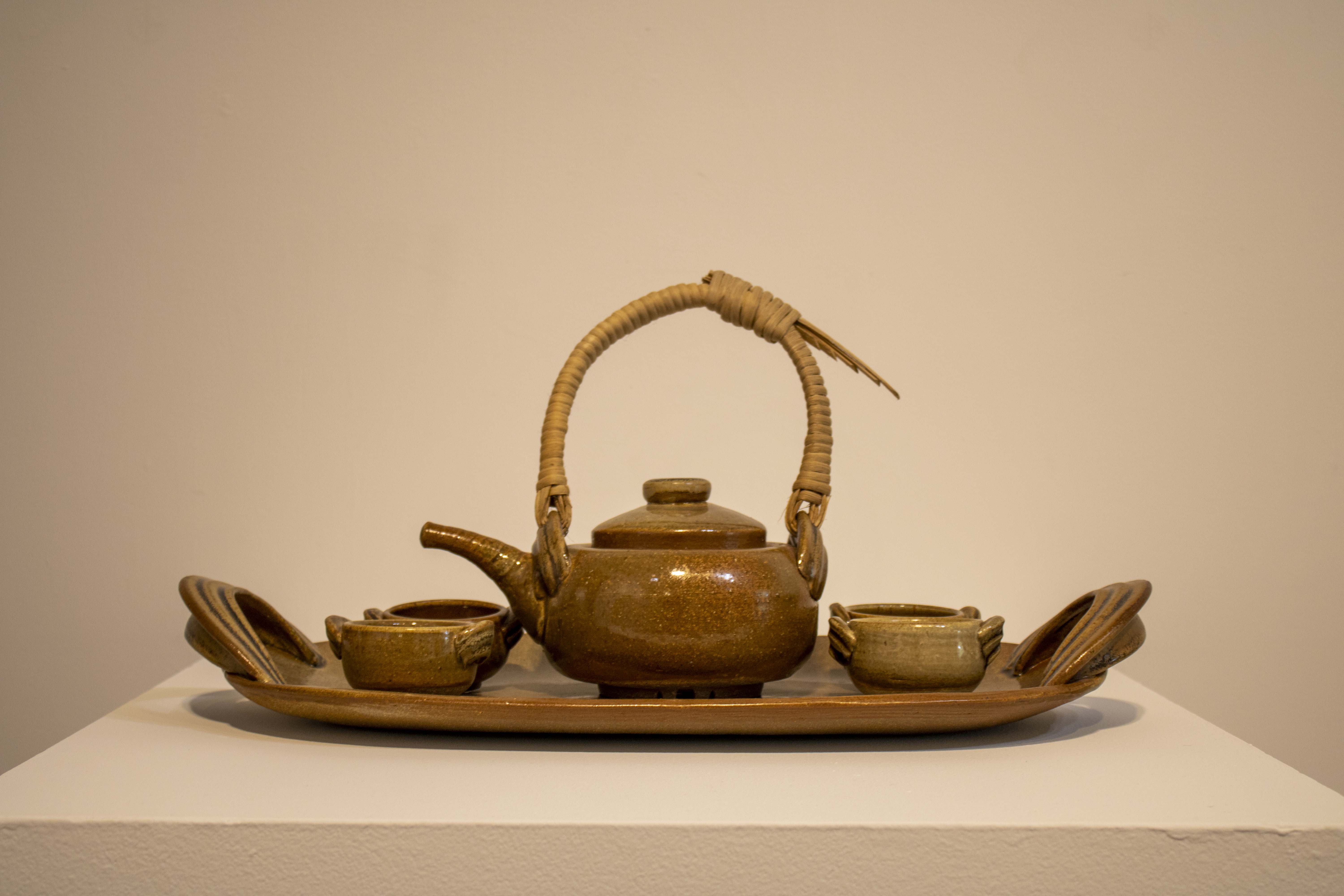 Ceramic platter with teapot and 4 cups. Teapot uses woven reeds as a handle.