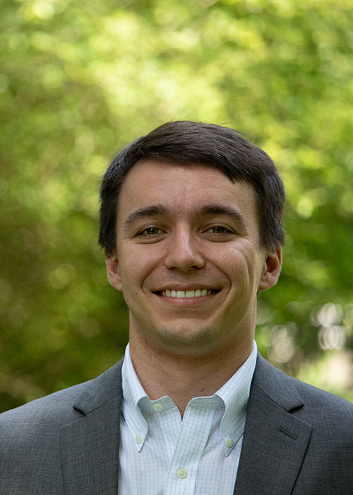 Rob Warlick headshot - outside, green shown in background