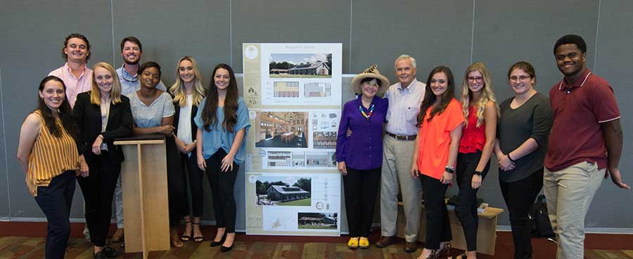 winning team poses with project board: From left to right, they include Brianna Brown, Chip Goza, Tori Thompson, Ryeley Jacobs, Malik Henley, Emily Purner, Megan Henry, Sheryl and Bob Bowen, Ashtyn Carpenter, Madison Holbrook, Danielle Leclercq and Caleb Shaw.