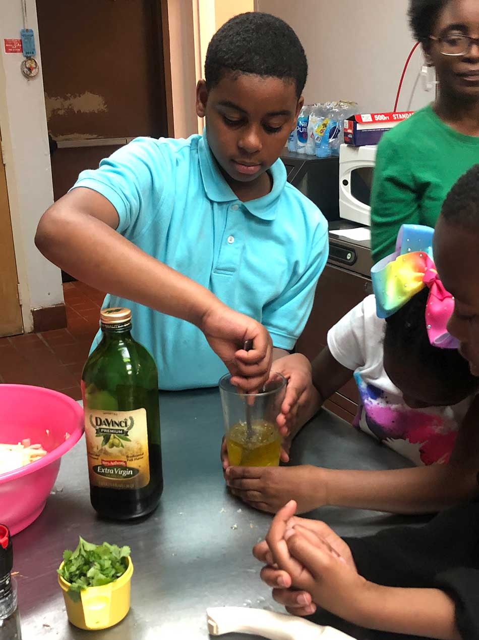 a boy stirs olive oil in a jar - looks to be making dressing