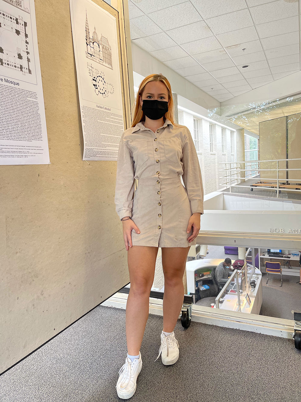 Savannah Wilson poses wearing mask in front of board with work in Giles Hall